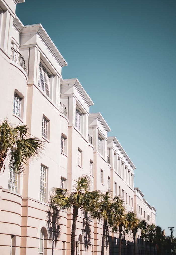 pexels photo 1838640 Bright modern building facade with palm trees against a clear blue sky.